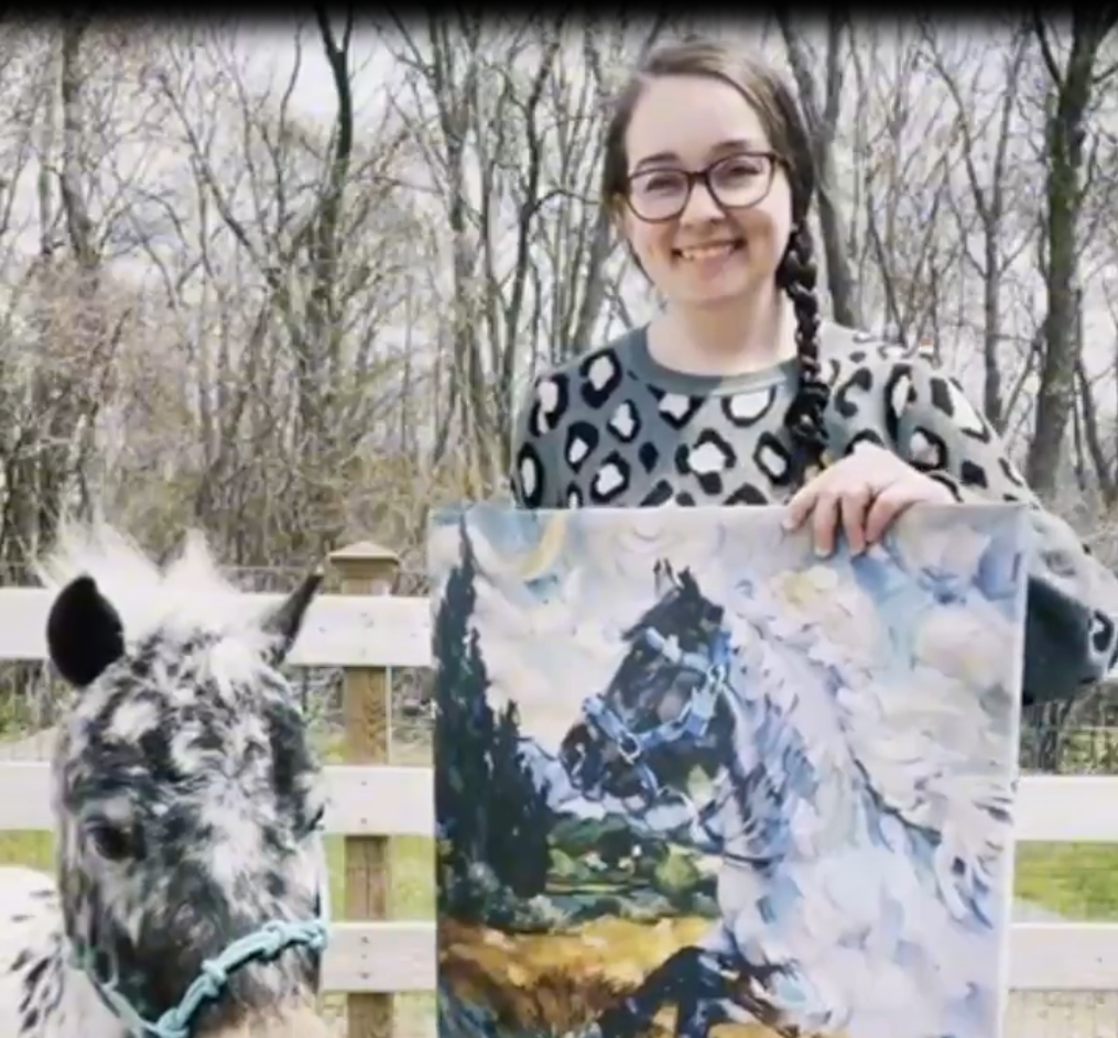 Customer holding a custom horse portrait canvas beside the photographed horse